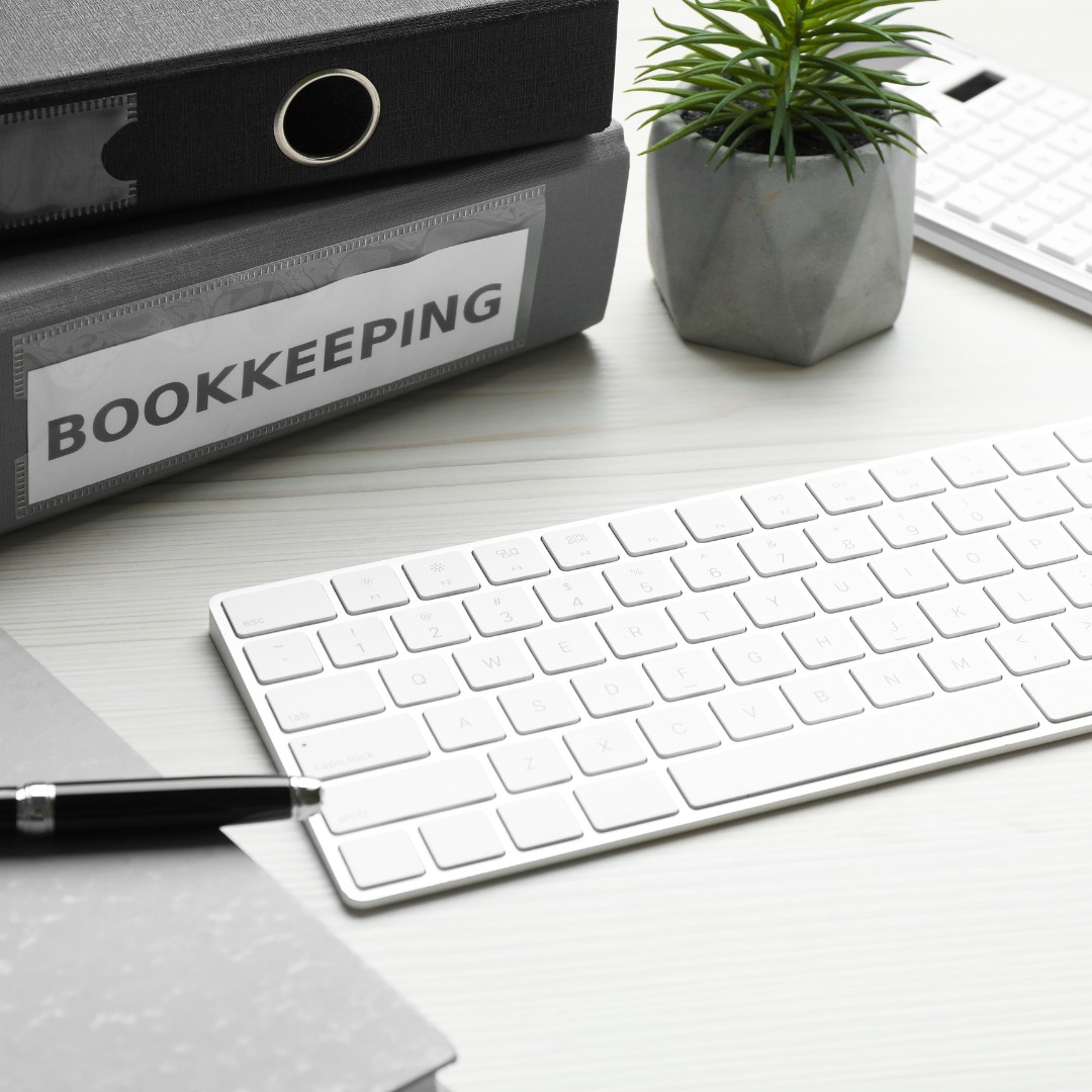 Keyboard, pen, folder entitled bookkeeping, small plant