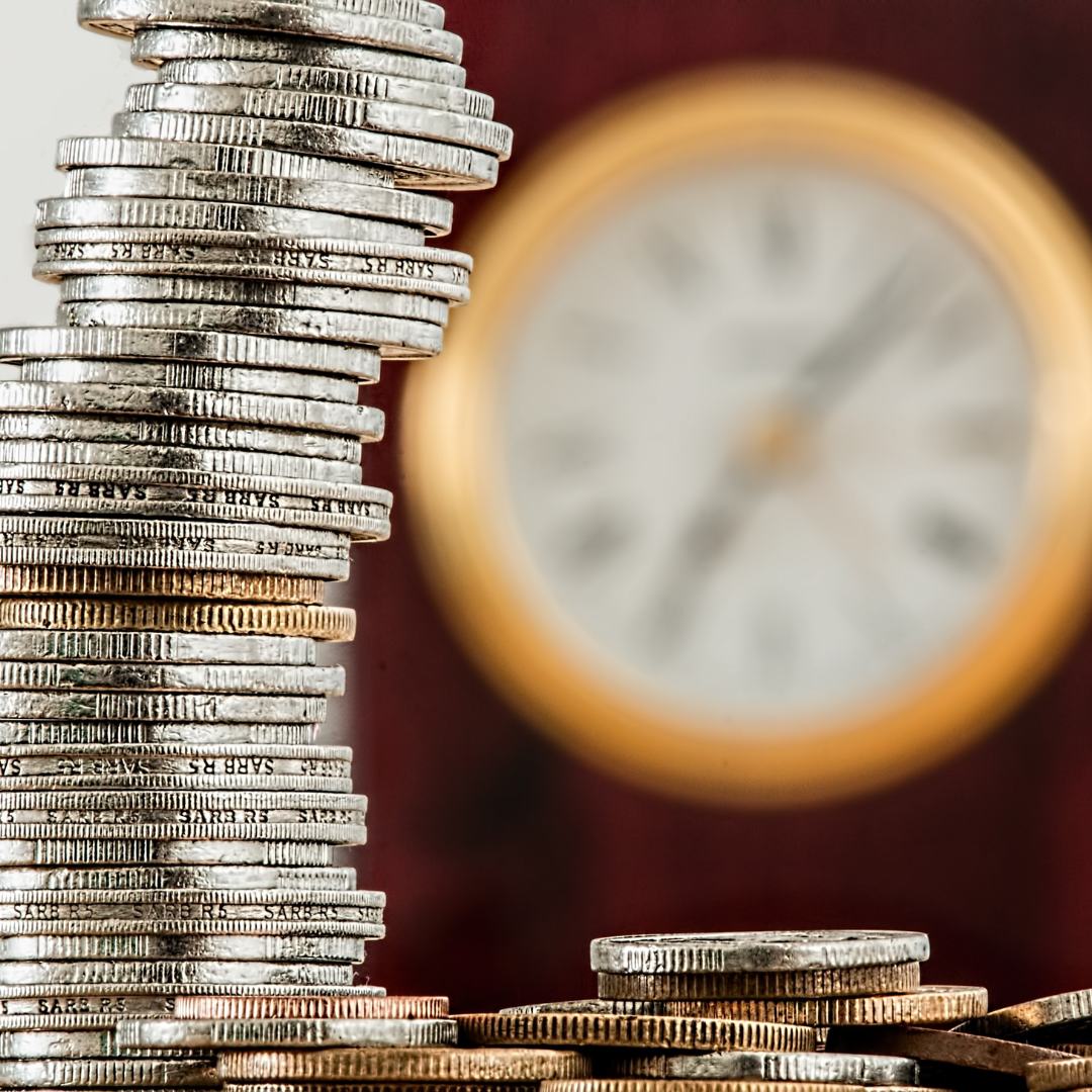 Stack of coins, clock in the background